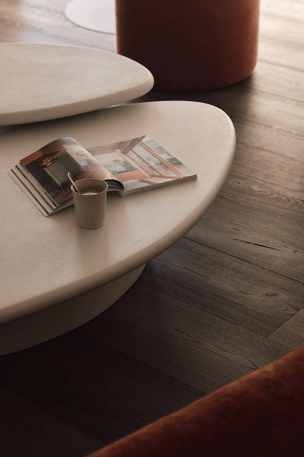 Twee créme kleurige salon tafeltjes met een decoratieboek en koffie.